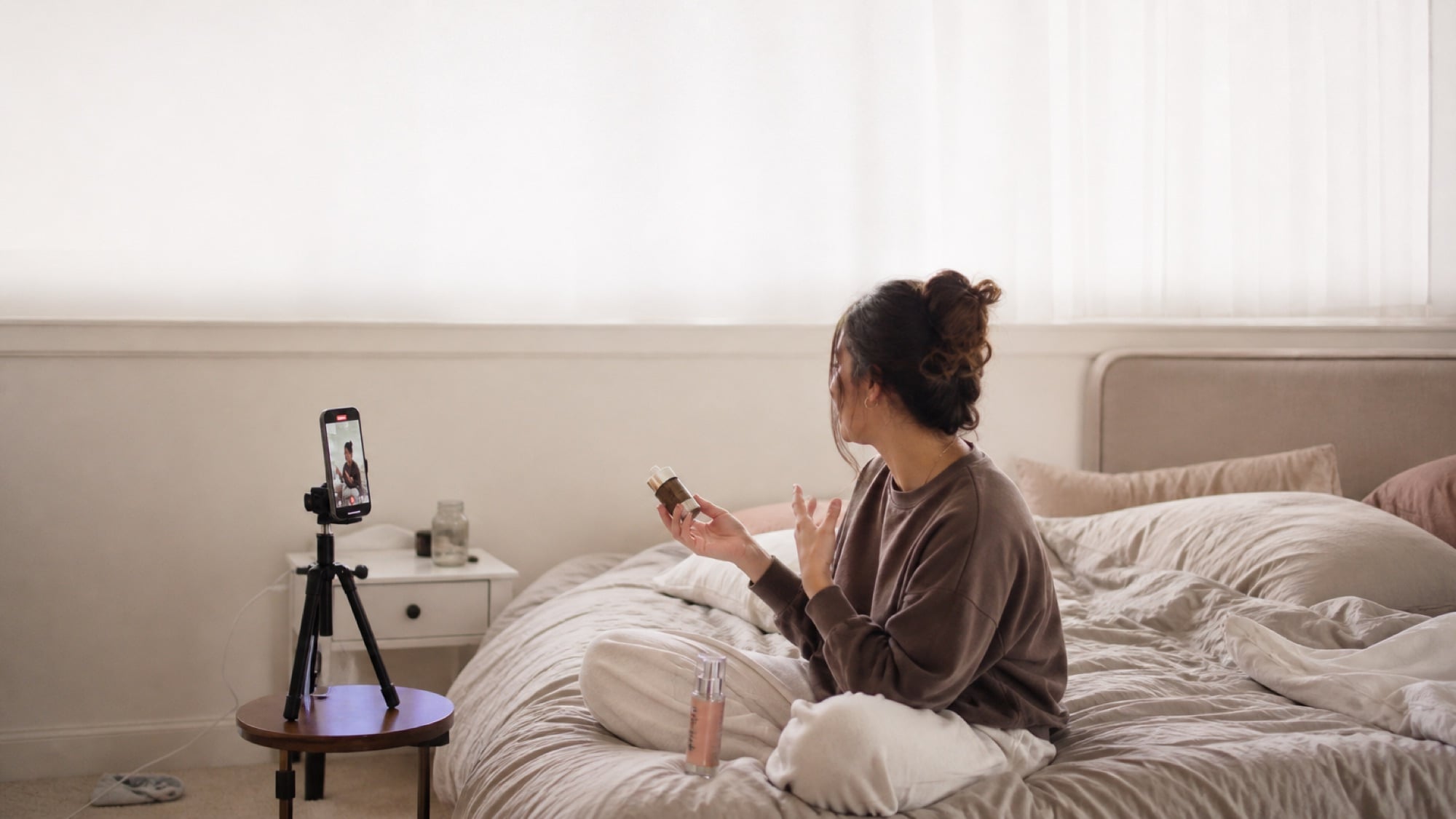 A creator recording a piece to camera at home with a phone on a small tripod.