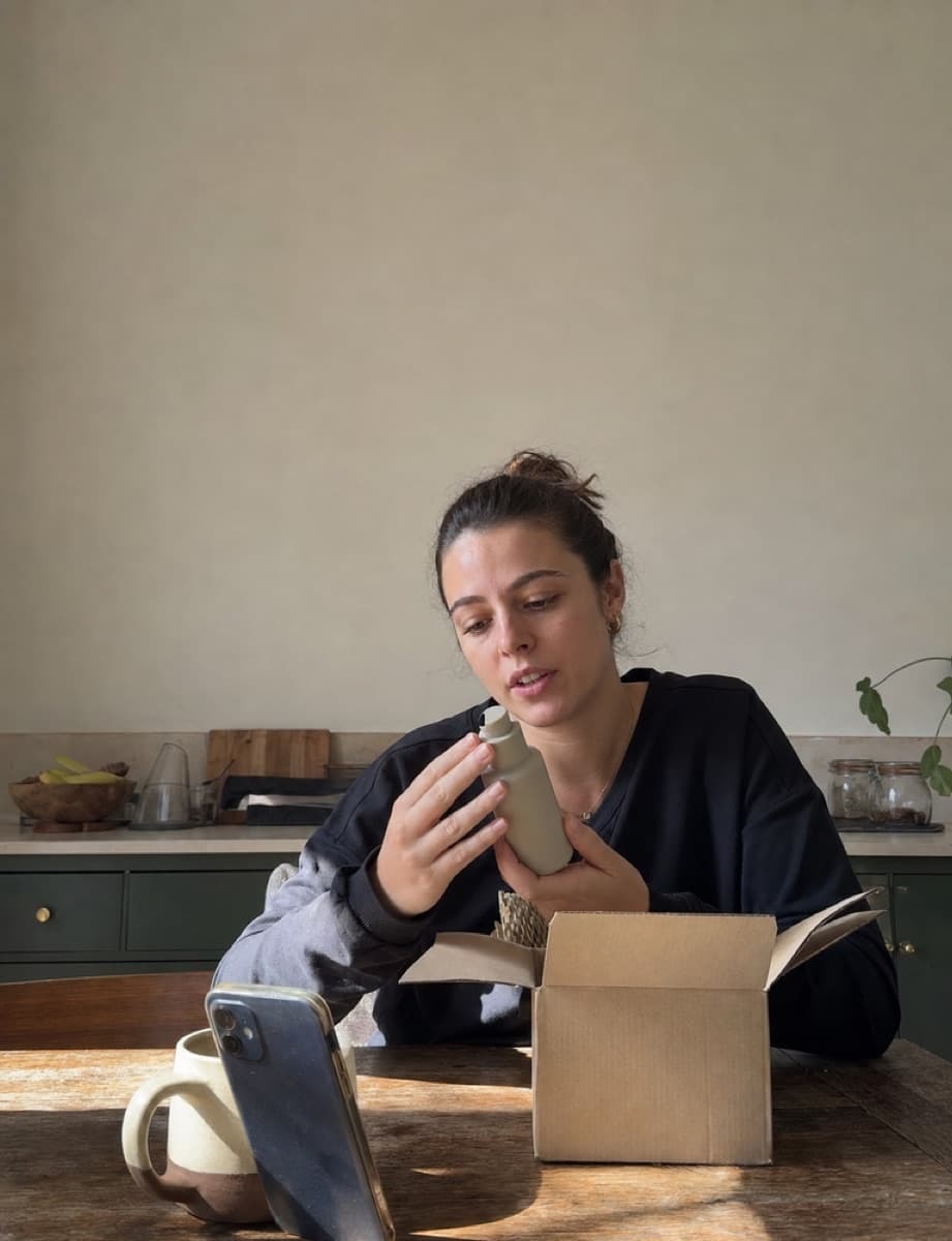 A creator unboxing a skincare product at her kitchen table.